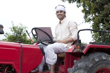 Portrait of a farmer with a laptop sitting on a tractor
