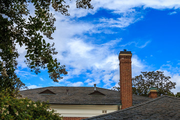 Fototapeta premium Roofs and chimney of an old southern mansion against a cloudy blue sky.