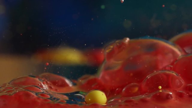 Slow motion, red bubble pops on water