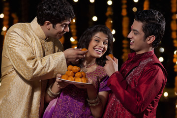 Two men tempting woman to eat sweets