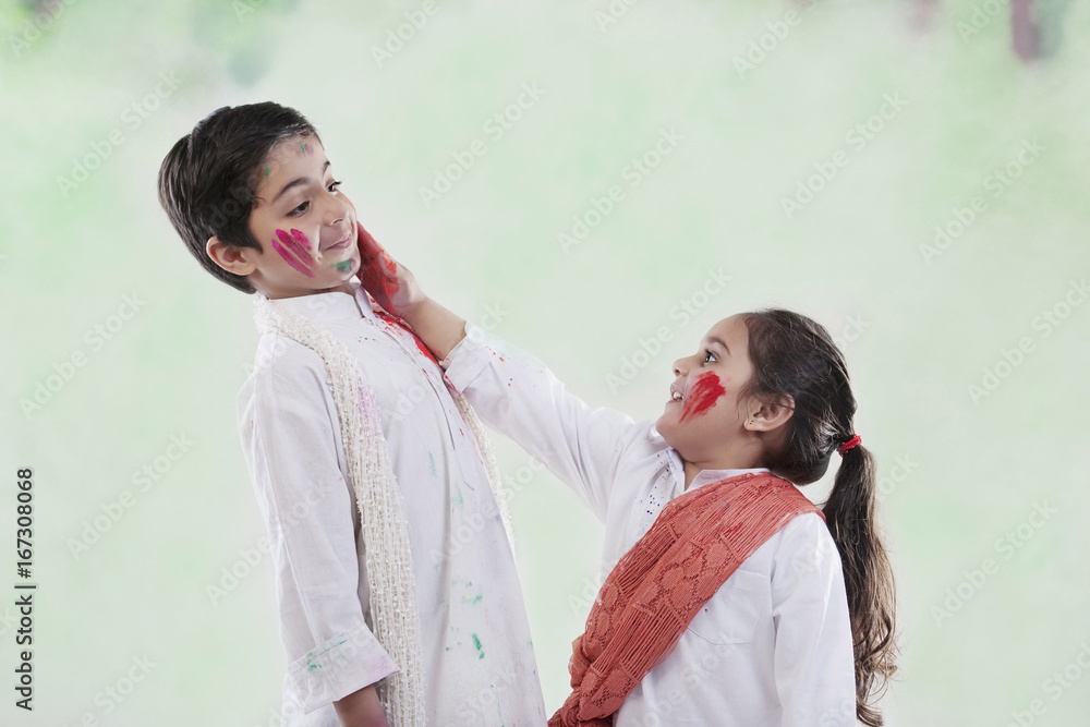 Wall mural girl putting colour on a boy's face