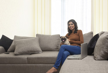 Obraz premium Young woman with pug sitting on sofa 