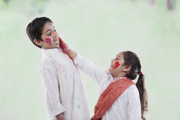 Girl putting colour on a boy's face 