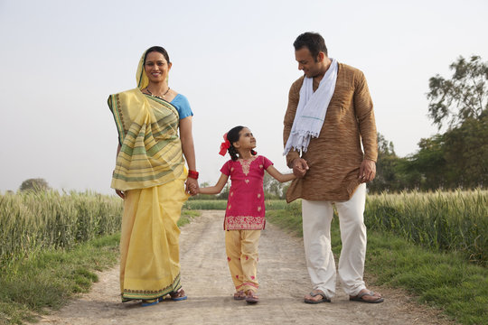 Full length of an Indian family walking on a rural road 