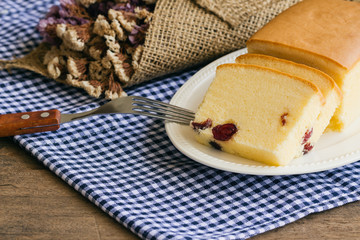 Slices of butter cake on white plate.Homemade butter cake with dried cranberries so delicious soft and moist.Tasty pound cake or butter cake served on wood table.Homemade bakery concept for background