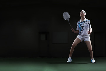 Fototapeta na wymiar Full length of young woman holding badminton racket at court