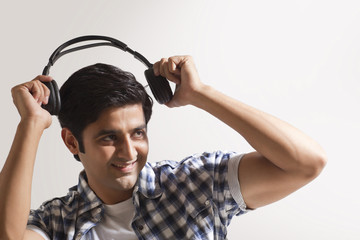 Handsome young man holding headphones and smiling 