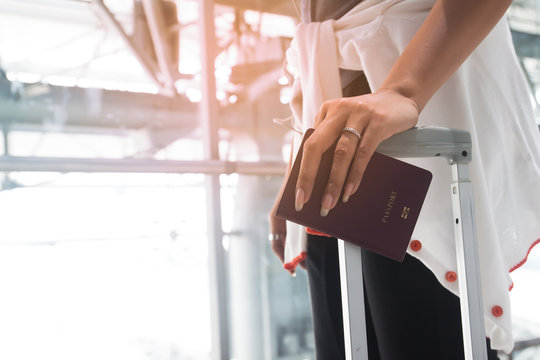 Close up of woman hand with engagement ring holding passport and suitcase, Travel concept