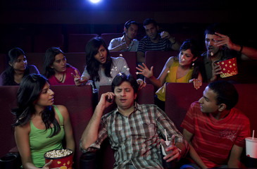 Man talking on a mobile phone in a cinema hall 