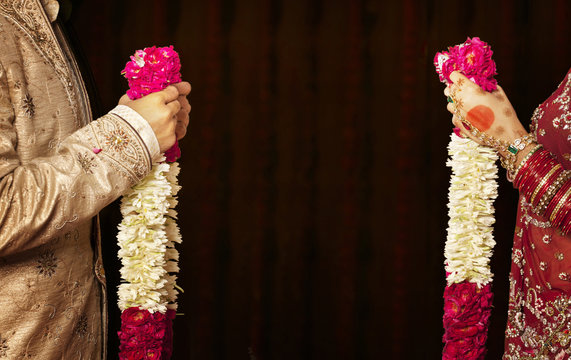 Close-up of bride and groom holding garlands 