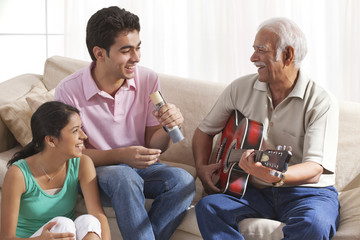 Grandfather playing the guitar and grandchildren singing - Powered by Adobe