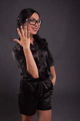 Fototapeta premium Young glad woman portrait of a confident businesswoman showing by hands on a black background. Ideal for banners, registration forms, presentation, landings, presenting concept.