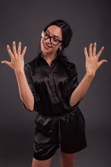 Young happy woman portrait of a confident businesswoman showing by hands on a black background. Ideal for banners, registration forms, presentation, landings, presenting concept.