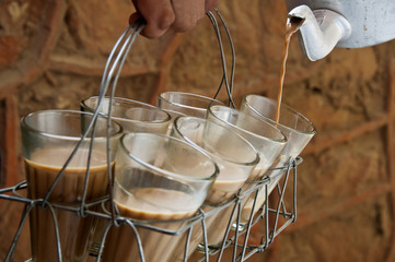 Chai being poured in glass through a tea kettle 