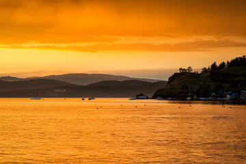 Scenic orange yellow sunset on the lake in a bay with yachts