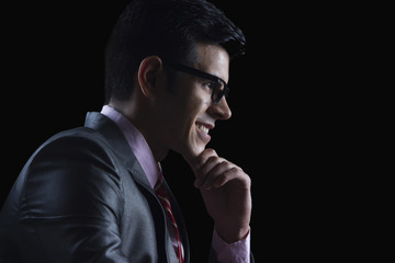 Side view of businessman with hand on chin against black background