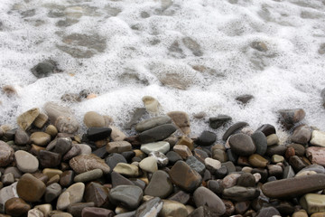 Fototapeta na wymiar pebble beach waves lap pebble as backgroun