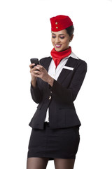 Young airhostess text messaging on cell phone isolated over white background 