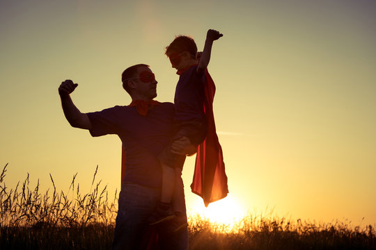 Father and son playing superhero at the sunset time.