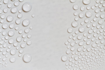 Big and small water drops on gray background. Closeup.