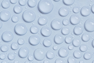 Big and small water drops on blue background. Closeup.
