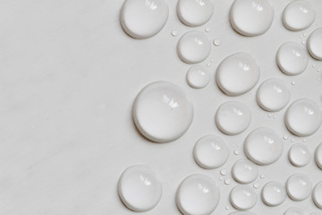 Big and small water drops on gray background. Closeup.