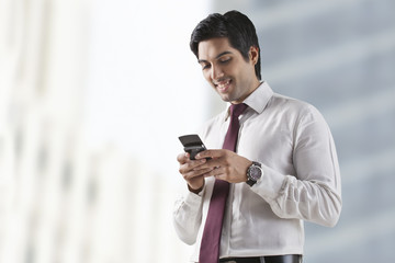 Confident young man text messaging on white background 