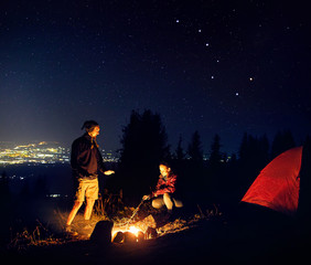 Romantic couple near campfire at starry night