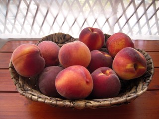 Ripe and fresh peaches in the basket on the veranda table.