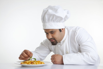 Chef decorating pasta with leaf
