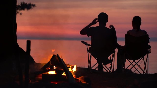 Couple is Sitting near Campfire at Night.