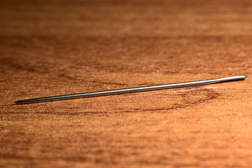 Sewing needle on a wooden background close up