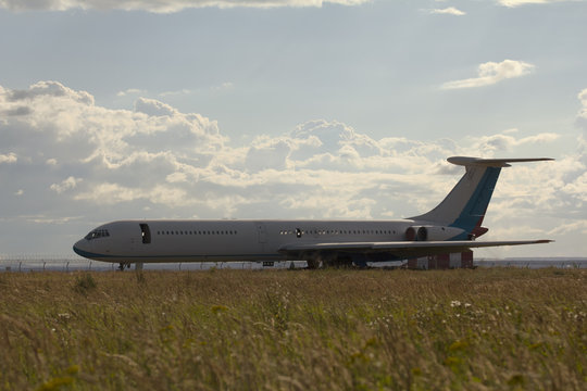 Dump of aircraft - old soviet civil passenger airplane in dield at summer day