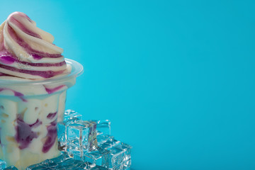 cup of strawberry flavor ice cream and ice cube on blue background with copy space