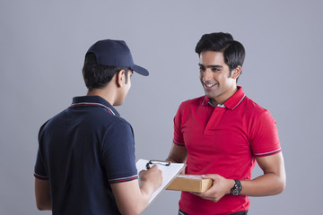 Delivery man delivering package to customer against gray background