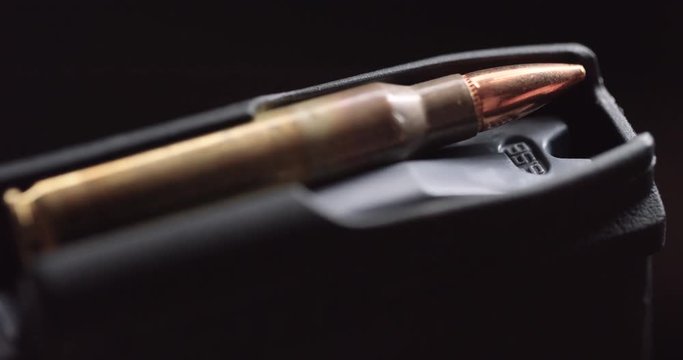 Close up, person places rifle bullets into magazine