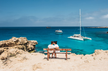 Loving couple sitting on a bench and looks at the lagoon. Honeymoon lovers. Man and woman on the...