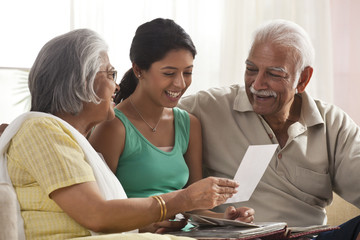 Granddaughter looking at a photo album with her grandparents