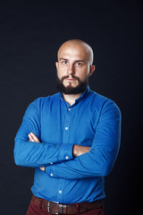 Portrait of a successful businessman on black background. Handsome bold man with beard