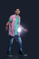 Full length of a confident teenage boy dancing against black background 