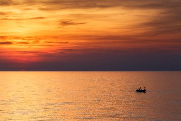A fisherman sailing on the sea in a boat at a beautiful sunset, Croatia, Europe.