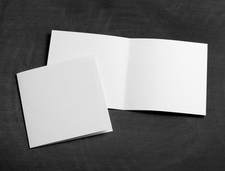 blank white folding paper flyer on a black chalkboard