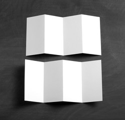 blank white folding paper flyer on a black chalkboard