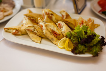 Rolled pancakes with smoked salmon on a buffet table, selective focus