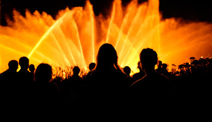 Fototapeta premium Girls in front of yellow fountain at night