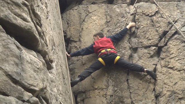 Young man rock climbing on a big natural rock