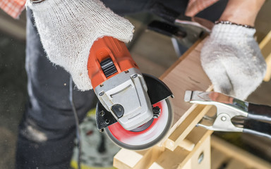 Worker grinds the wood of angular grinding machine