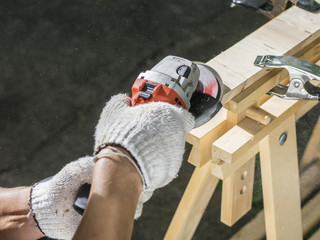 Worker grinds the wood of angular grinding machine