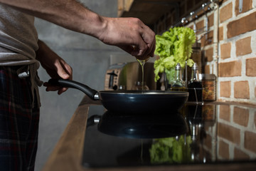 partial view of young man preparing eggs for breakfast in kitchen at home