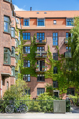 Facade of red brick Building with Balconies and Ivy, Copenhagen, Europe